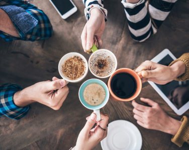 Four people's hands holding mugs of coffee.