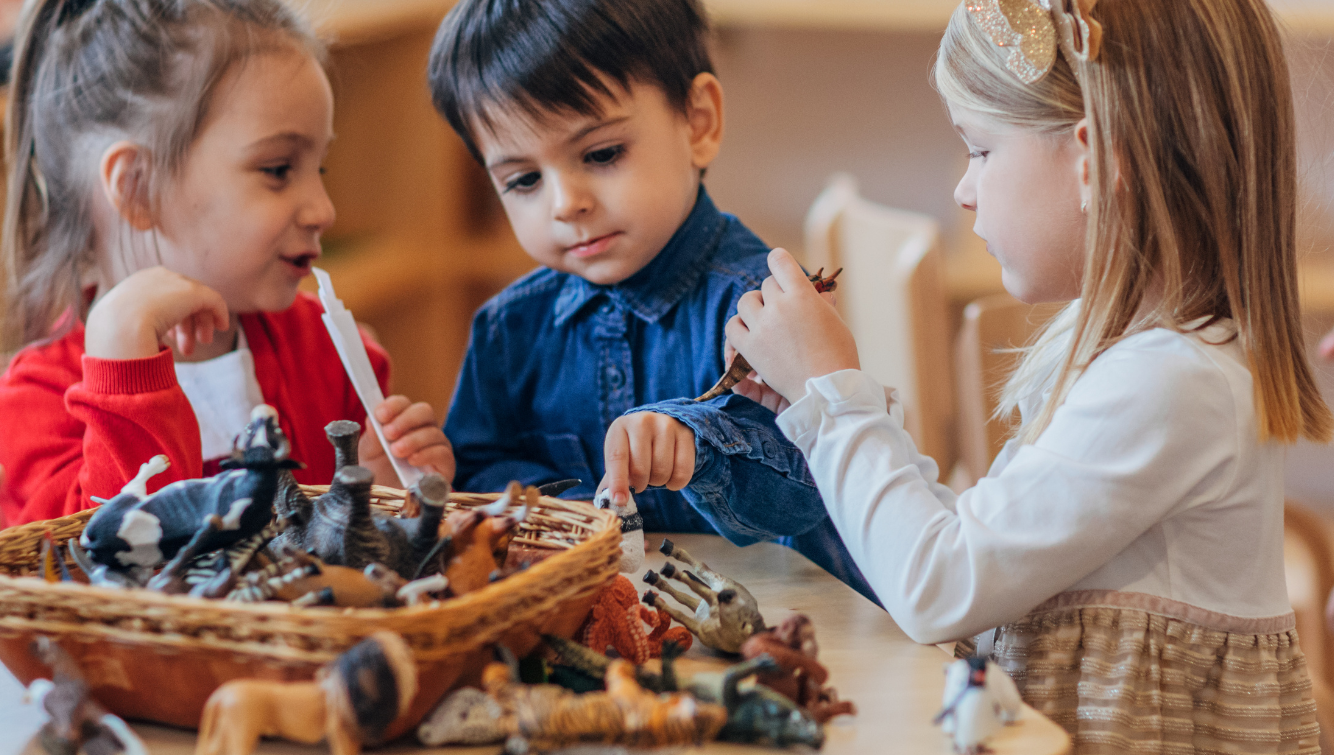 Children playing at a table with toy animals.