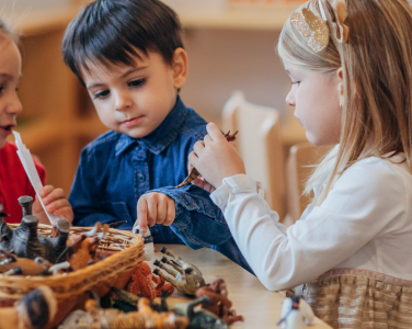 Children playing at a table with toy animals.