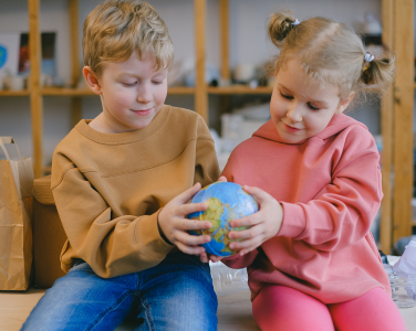 Two children holding a small globe.