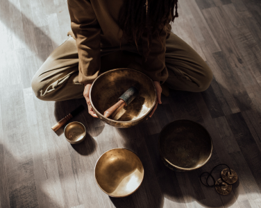 A person sitting on the floor with singing bowls.