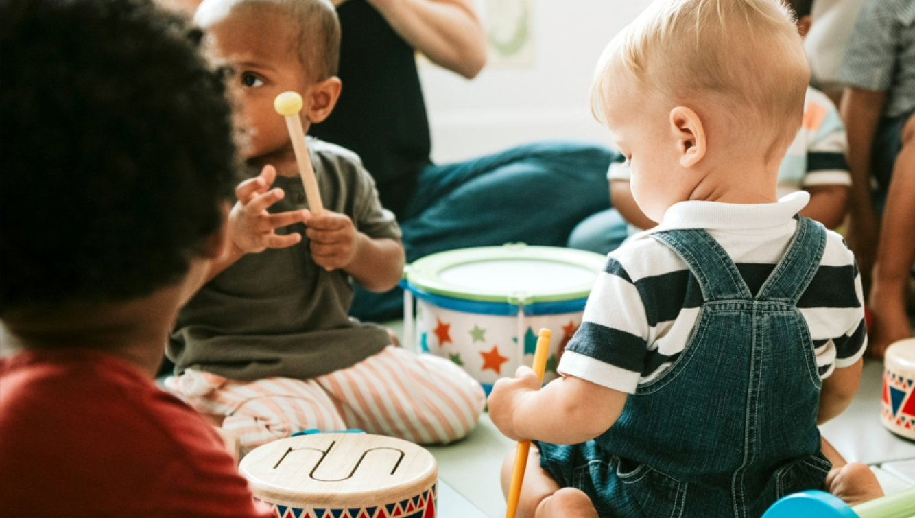 Toddlers playing with colourful drums and instruments.