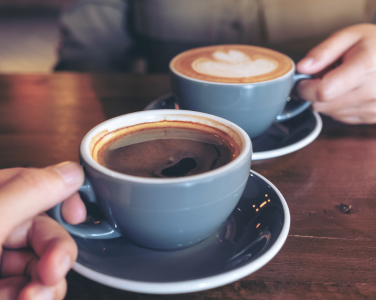 Two blue cups of coffee on a wooden table.