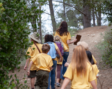 Group of children and an adult walking on a forest trail.