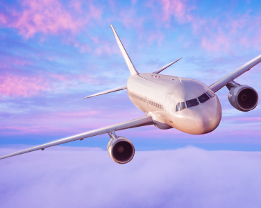 Airplane flying through a pink and purple sky.