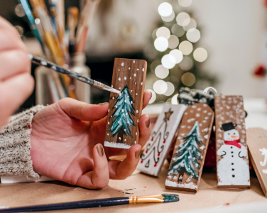 Close-up of a person painting wooden Christmas ornaments.