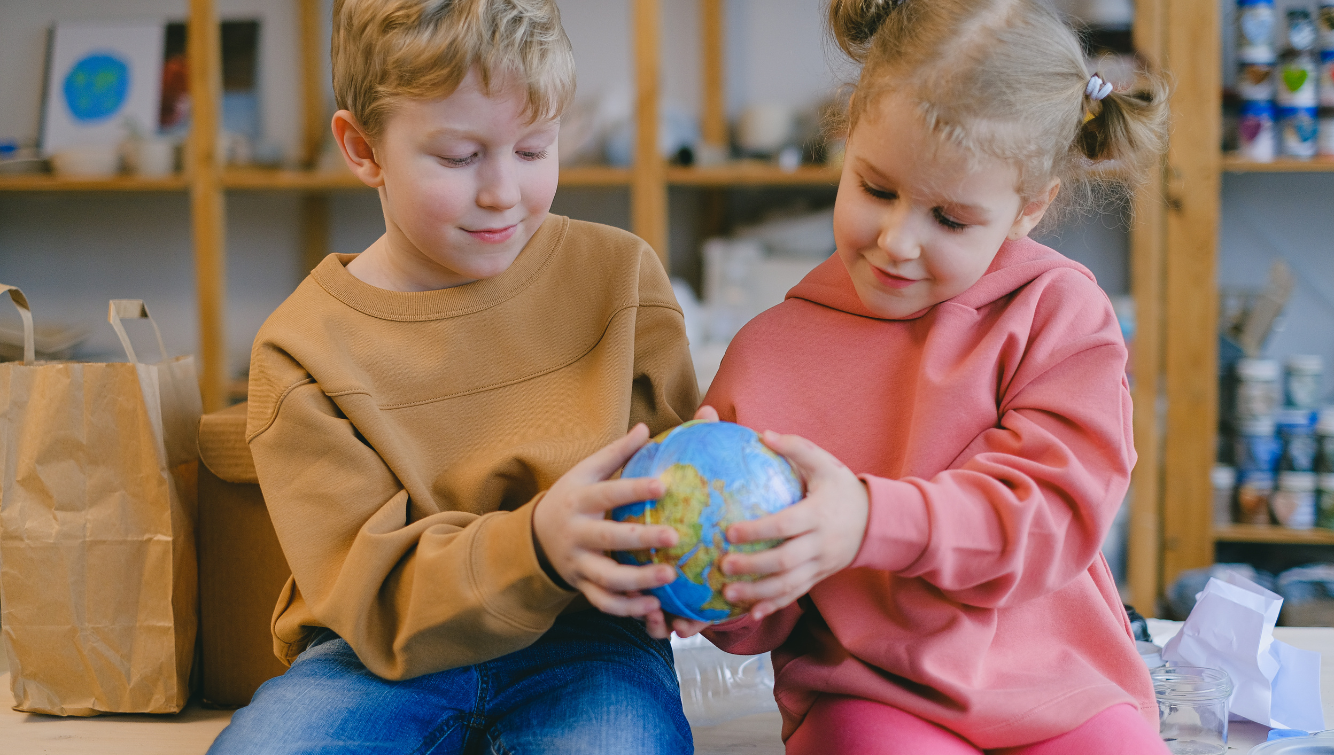 Two children holding a small globe.