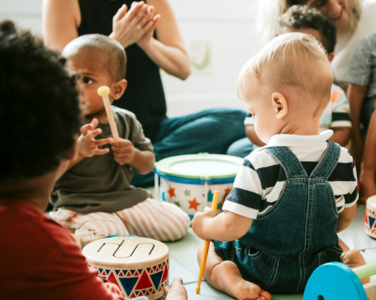 Toddlers playing with colourful drums and instruments.