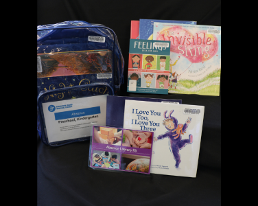 A display of children's books and an educational backpack kit.