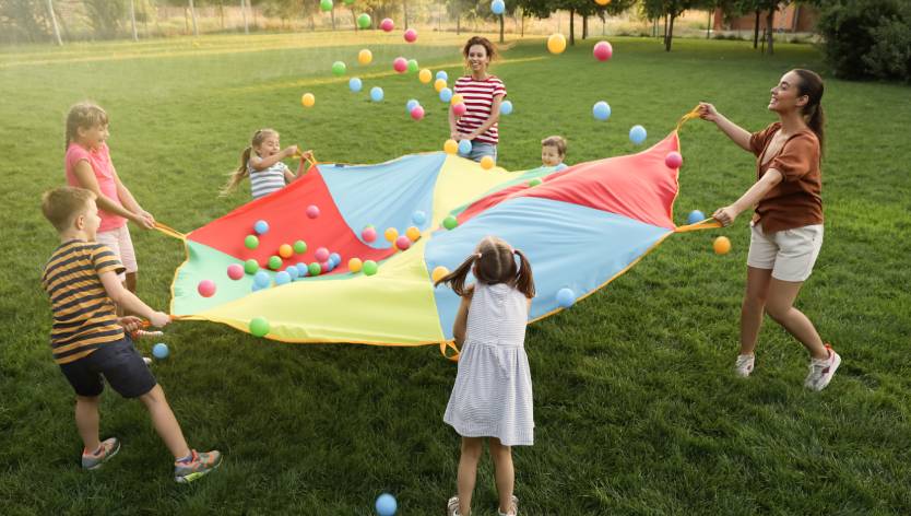 kids playing outside with a parachute and balls