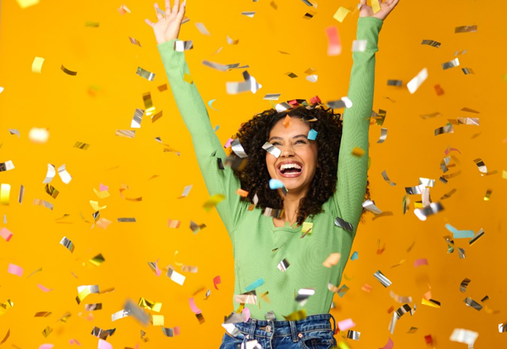 A woman in a green shirt celebrating as metallic confetti falls