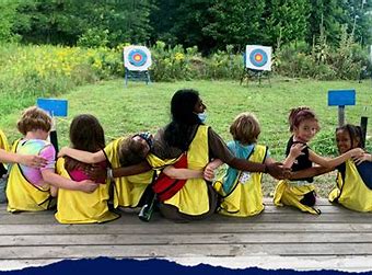 camp kids sitting on a desk with their arms around each other