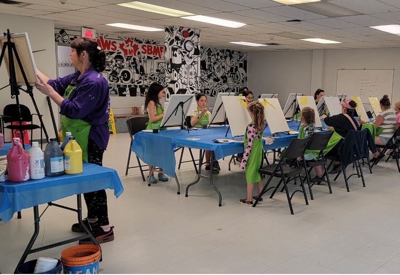 Group of people painting on canvases during a guided paint night event.