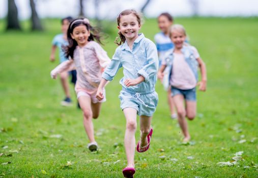 Children running and smiling on grassy field