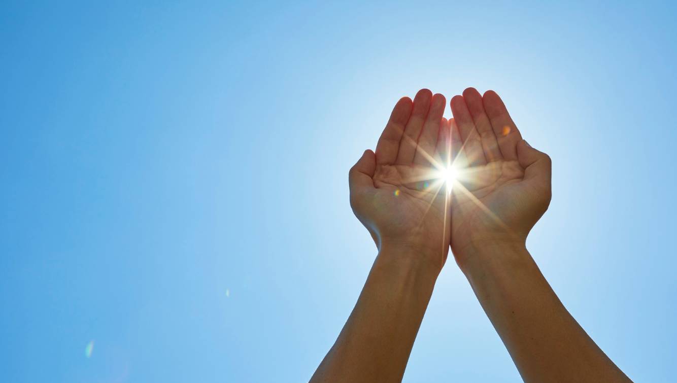 Hands Capturing Light Against a Clear Sky