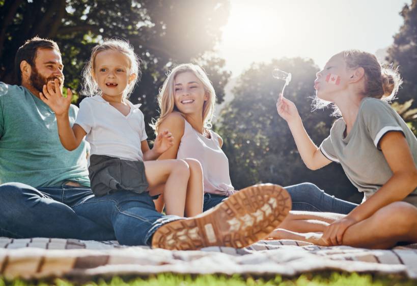 Happy family, picnic and summer, fun in park with children and parents bonding and playing on grass.