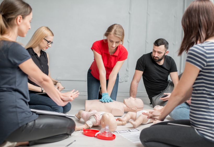 Young women instructor showing how to make chest compressions