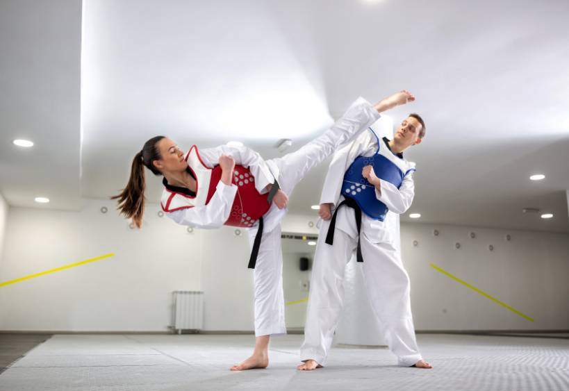 Young woman training martial art of taekwondo with her coach
