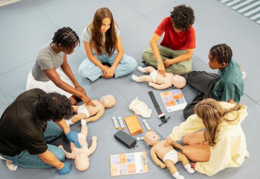 Children on floor with baby dolls practicing CPR