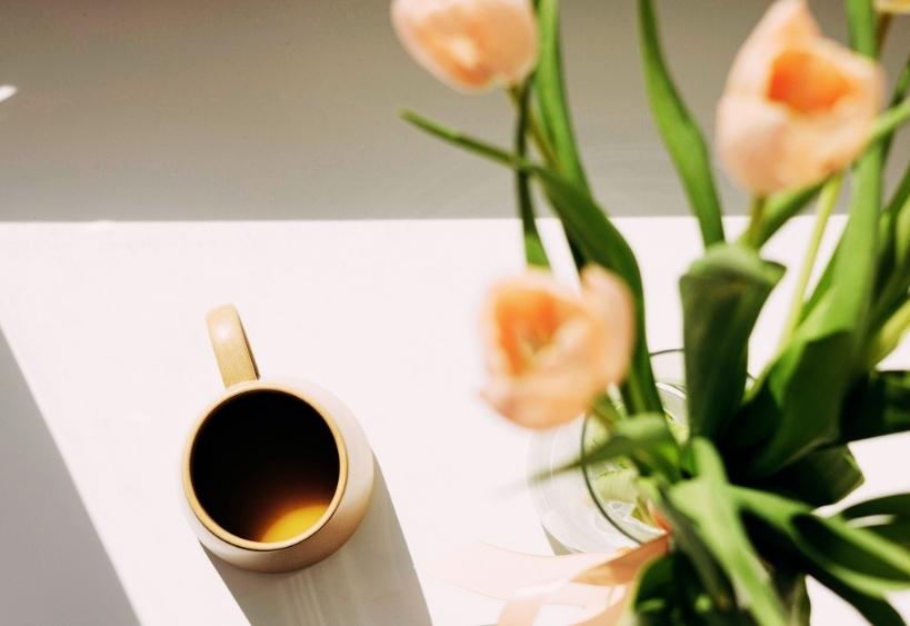 Cup of coffee beside bouquet of pink tulips