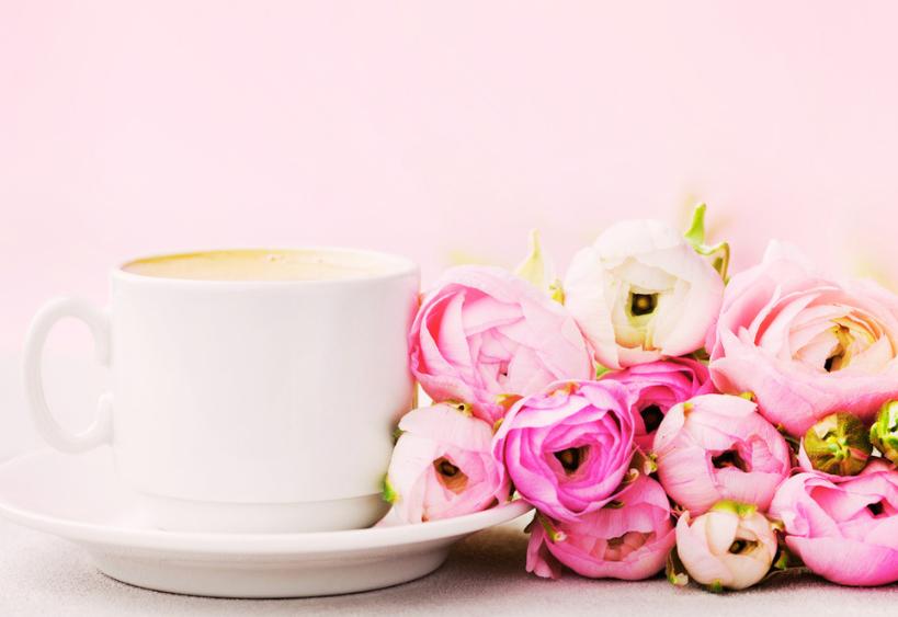 Cup of coffee beside bouquet of roses