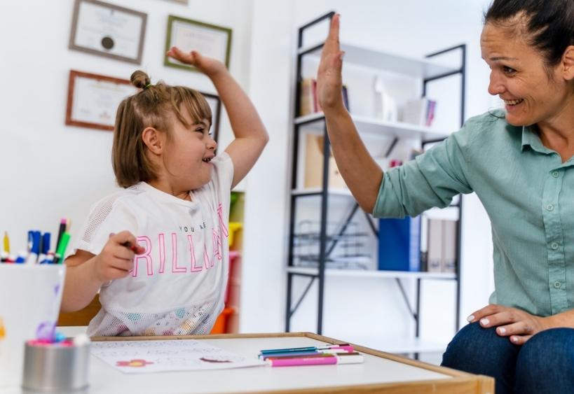 teacher and small girl with Down syndrome giving high-five