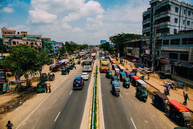 Vibrant urban street bustling with traffic and pedestrians under a bright sky