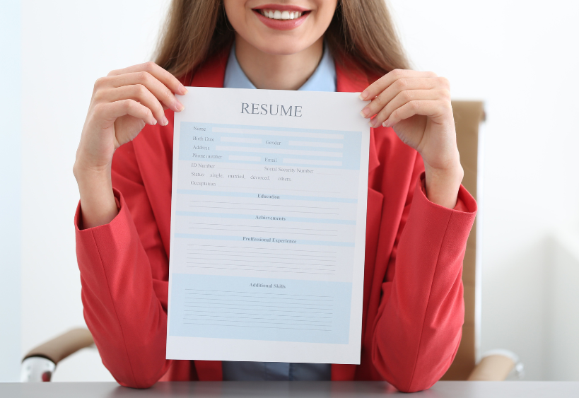 Confident woman in a red blazer proudly presenting her resume—ready to turn potential into opportunity