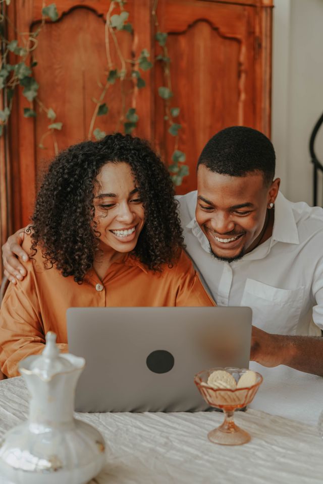 Smiling couple sitting together with a laptop at a table