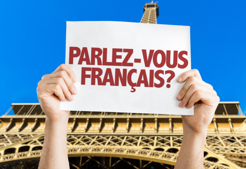 A sign that says ‘Parlez-vous français?’ in front of the Eiffel Tower.