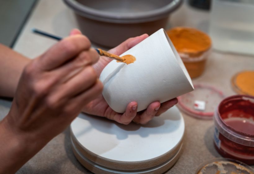 Someone painting a ceramic cup