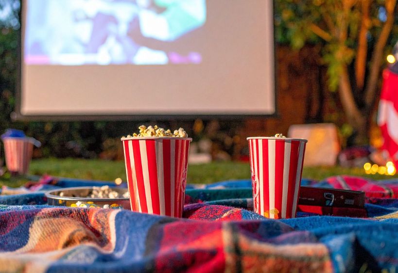 Blanket and popcorn in front of an outdoor movie screen