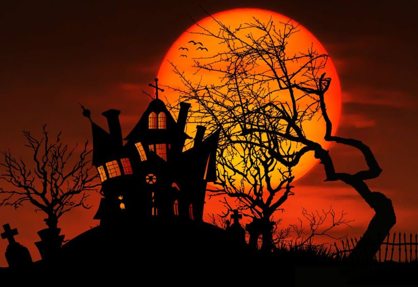 A silhouetted haunted house stands among bare trees against a large orange full moon, creating a classic Halloween scene.