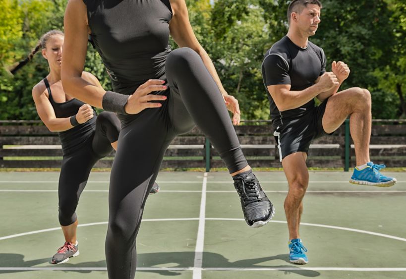 Three people are participating in an outdoor fitness exercise session.
