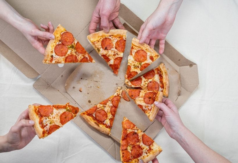 hands holding slices of pizza