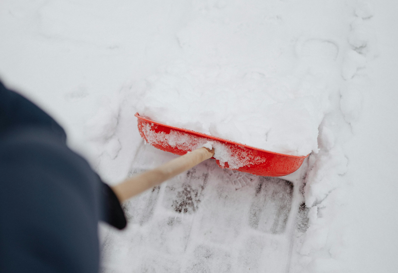 Snowy sidewalk being cleared with shovel