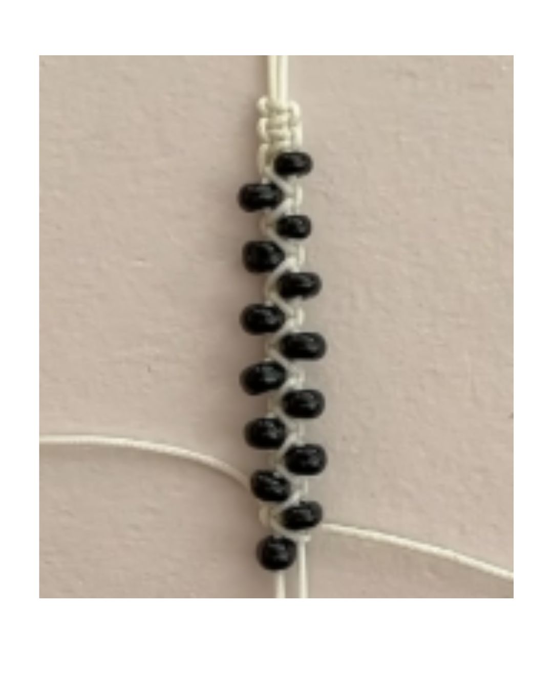 bracelet or necklace made with white cord and black beads