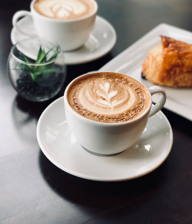 two lattes with latte art on a black cafe table