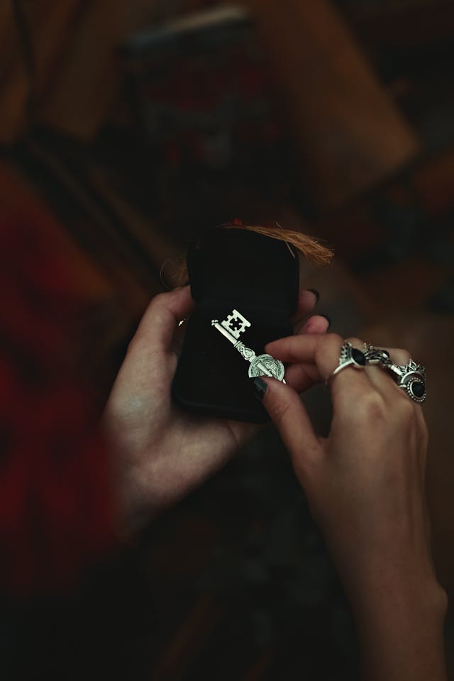 Close-up of hands holding an elegant key-shaped pendant in a box.