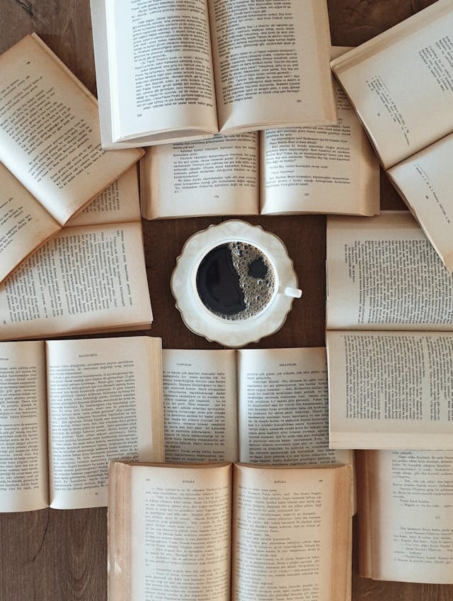 Flat lay of open books surrounding a coffee cup, perfect for a relaxing reading atmosphere.