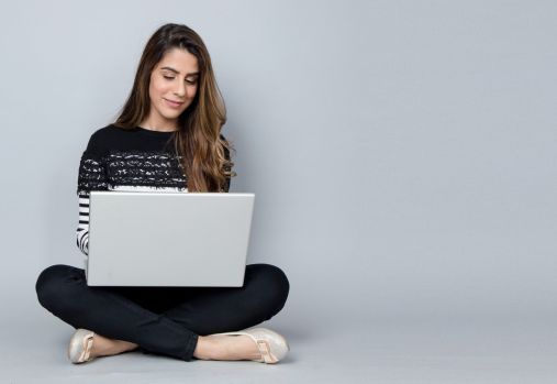woman sitting cross-legged looking at laptop