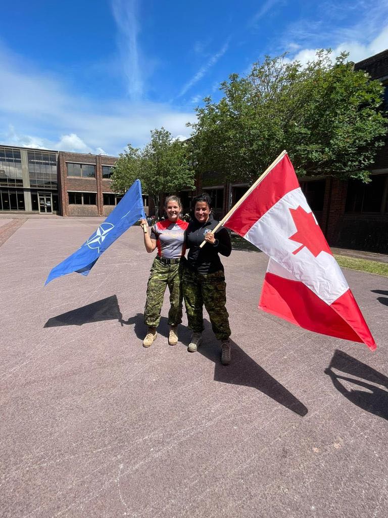 Claudine and Sarah-Emilie holding a NATO flag and a Canadian flag