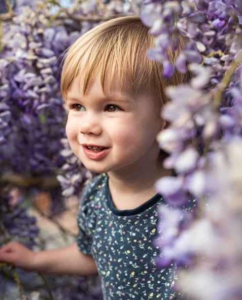 girl peering out from the wisteria
