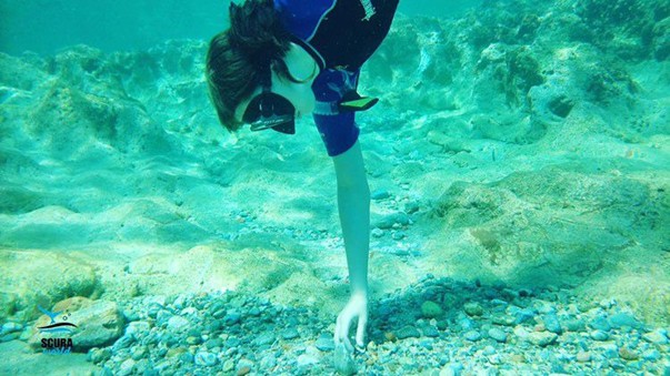 boy scuba diving and reaching to bottom of sea floor