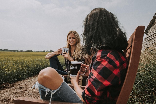 two friends having coffee next to a field