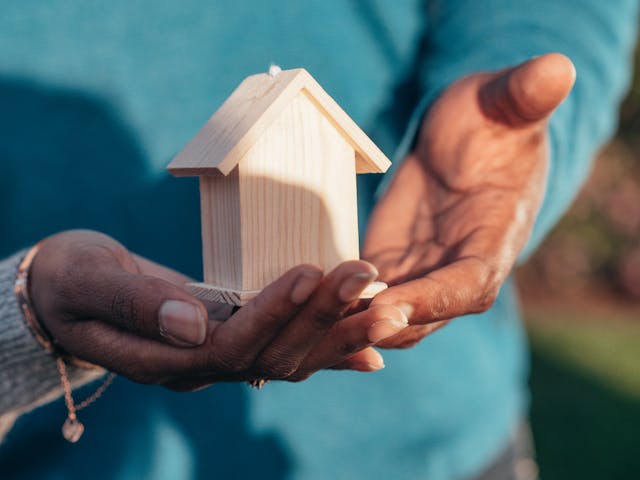 People Holding Miniature Wooden House