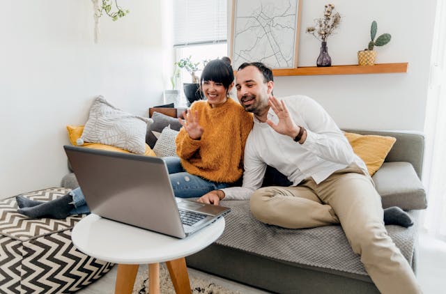 Man in White Long Sleeves and Woman in Yellow Fur Long Sleeves Video Calling on Laptop