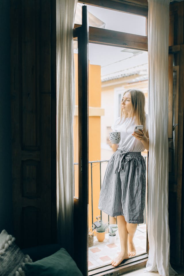 Woman Standing in the Balcony While Holding a Mug
