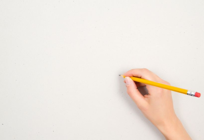 hand holding pencil, drawing on white paper.