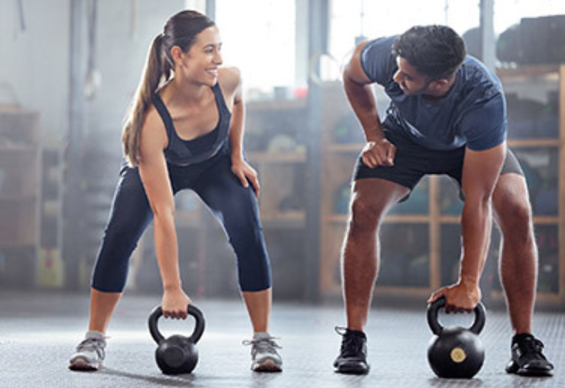Woman and man lifting kettlebells